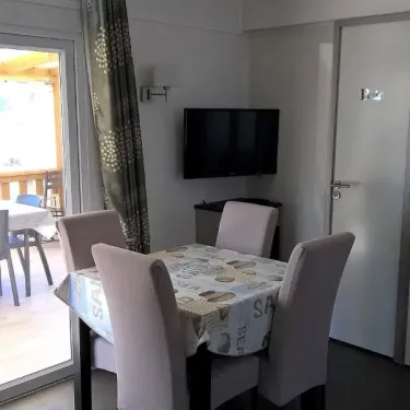 Salon avec table à manger et télévision dans le Mobil Home Grand Confort 3 Chambres au Domaine de L'Auzance