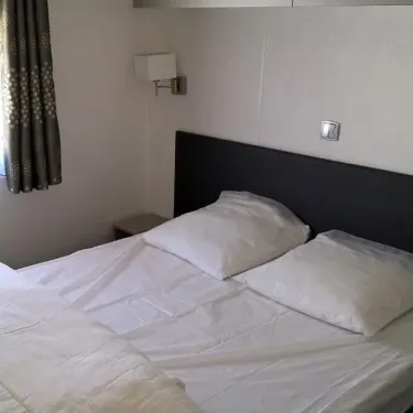 Chambre avec lit double et tête de lit noire dans le Mobil Home Grand Confort 3 Chambres au Domaine de L'Auzance