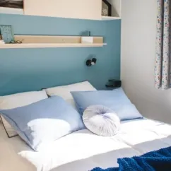 Lit double avec couvre-lit bleu et oreiller rond dans Mobil Home Aqua