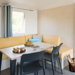 Coin repas avec canapé jaune et table dans Mobil Home Aqua