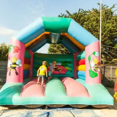 Enfants jouant dans un manège gonflable à thème abeille au Camping Club Mahana