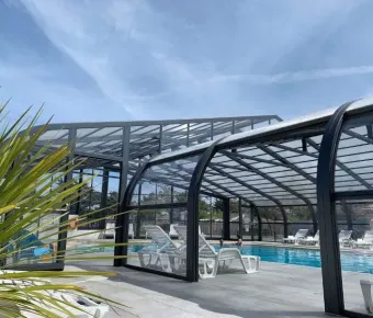 Piscine couverte avec transats blancs au Camping Club Mahana