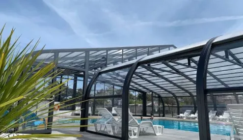 Piscine couverte avec transats blancs au Camping Club Mahana
