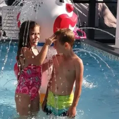 Camping Club Mahana : enfants rieurs sous un jet d'eau de fontaine ludique
