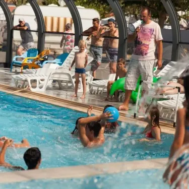 Camping Club Mahana : enfants et adultes jouent joyeusement autour d'une piscine avec un toboggan