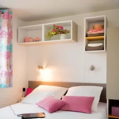 Chambre avec lit double, étagères murales et coussins roses - Mobil Home Fidji - Le Bellevue