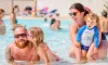 Famille souriante dans la piscine au Camping Les Bruyères