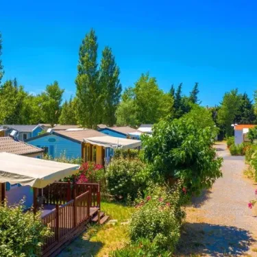 Village de cabanes colorées entouré d'arbres et de fleurs au Camping Ensoya.