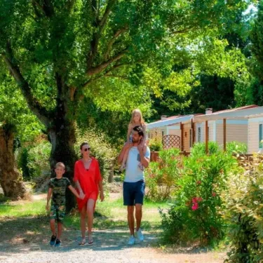 Famille à Camping Ensoya, marchant sous grands arbres près de mobil-homes.