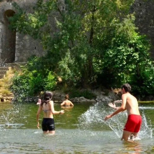 Des visiteurs s'amusent dans une rivière près d'un château historique.