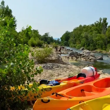 Kayaks jaune et orange sur rive rocheuse du Camping La Plage de l'Orb.