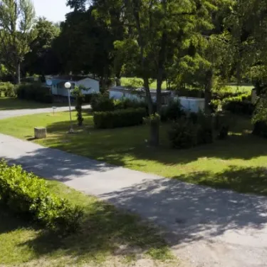 Camping Le Plantaurel avec voies pavées, arbres et mobil-homes verdoyants