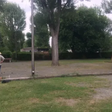 Camping Le Plantaurel : deux personnes dans un espace vert avec arbres et une cabane en arrière-plan.