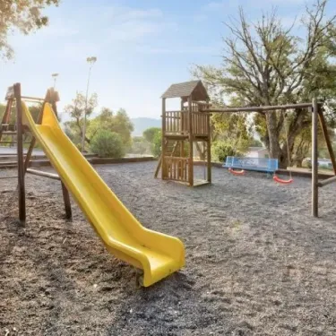 Zone de jeux pour enfants avec toboggan jaune au Camping Le Parc des Chênes