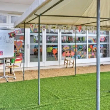 Espace enfant avec tente, affiches colorées et table d'accueil au Camping Le Parc des Chênes.