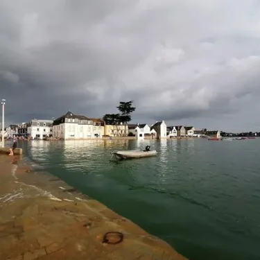 Vue du port de la ville sous un ciel orageux, eaux calmes et bateau au milieu