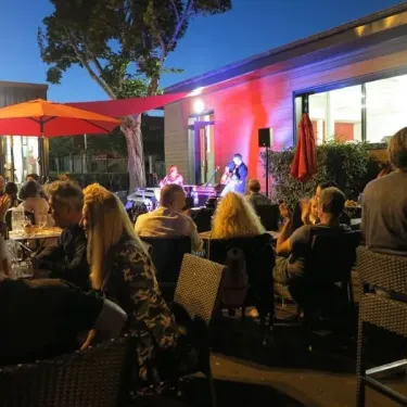 Camping Chanset : soirée avec musique live sous parasols rouges, ambiance nocturne.