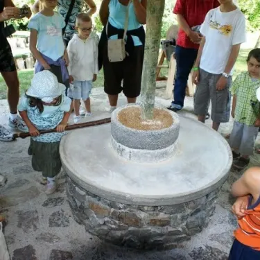 Enfant qui utilise un moulin à pierre au Camping Chanset