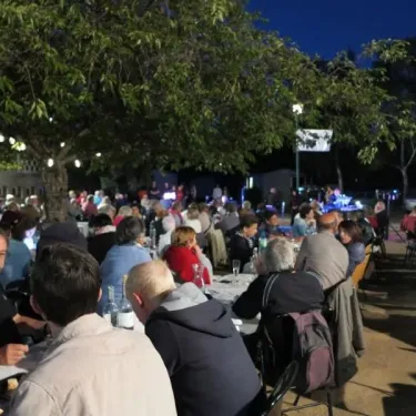 Camping Chanset : groupe d'adultes autour de tables sous un arbre, soirée festive en extérieur.