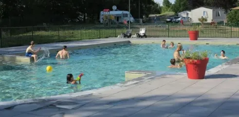 Camping Chanset : enfants qui jouent dans la piscine avec un ballon jaune.