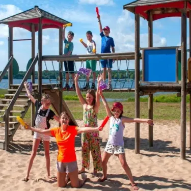 Enfants joyeux sur un parcours de jeu en bois près d'une plage à Camping Aurilandes