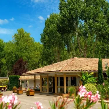 Office du Camping Aurilandes entouré de fleurs et arbres