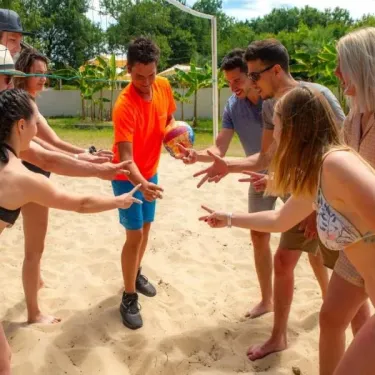 Groupe de personnes jouant au beach-volley sur le sable à Camping Aurilandes