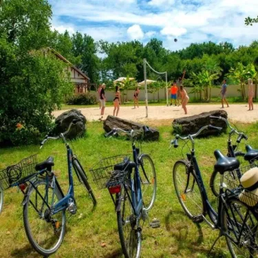 Bicyclettes stationnées près d'un terrain de beach-volley à Camping Aurilandes