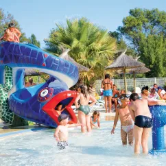 Piscine avec toboggan de serpent bleu et enfants qui jouent dans l'eau au Camping Domaine les Fleurs d'Agde