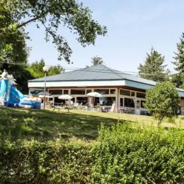 Camping Yaloer : bâtiment avec toboggan gonflable et parasols sur une pelouse verdoyante