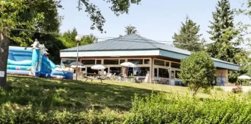 Camping Yaloer : bâtiment avec toboggan gonflable et parasols sur une pelouse verdoyante