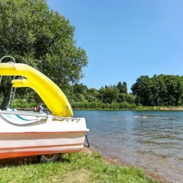 Camping Yaloer : bateau à pédale avec toboggan jaune près d'un lac, sous un arbre