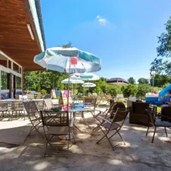 Camping Yaloer : terrasse extérieure avec tables, chaises et parasol bleu-vert