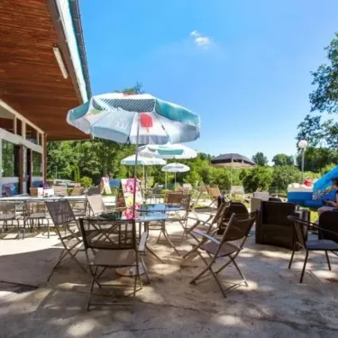 Camping Yaloer : terrasse extérieure avec tables, chaises et parasol bleu-vert