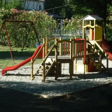 Camping Le Lion - aire de jeux enfants avec toboggan rouge, balançoire et structure en bois