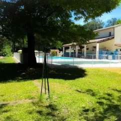 Camping Le Lion : maison traditionnelle avec piscine en fond, encadrée par une végétation luxuriante.