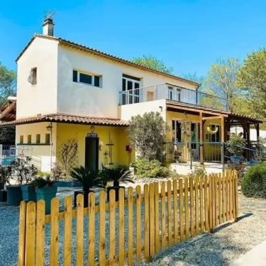 Maisons de campagne jaunes avec piquet en bois et jardin devant une maison traditionnelle.
