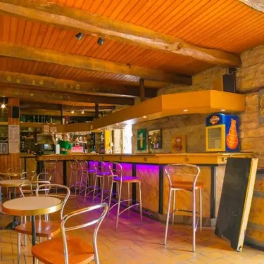 Intérieur d'un bar rustique avec tabouret et mur en pierre au Camping de La Plage - 29