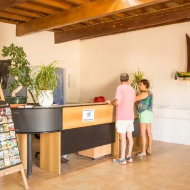 Reception du camping avec deux visiteurs, plantes et affiche de brochures, Camping Saint Maurice