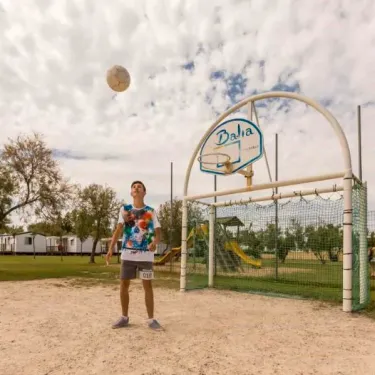 Enfant jouant au ballon près d'un panier basket avec le logo Camping Saint Maurice