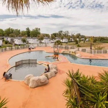 Piscine entourée de chaises longues et de végétation au Camping Saint Maurice