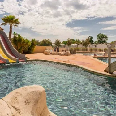 Piscine avec toboggan coloré et pont en bois au Camping Saint Maurice
