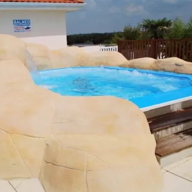 Piscine à débordement décorée en roche au Camping La Riviera