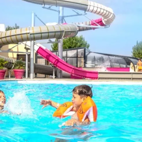 Enfants nageant dans une piscine avec toboggan aquatique Camping L'Océan