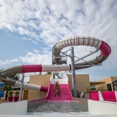 Camping L'Océan : toboggan aquatique rose et blanc en plein air sous un ciel bleu.