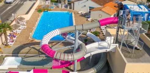 Vue aérienne d'une piscine avec toboggan rose et structure aquatique Camping L'Océan
