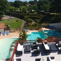 Piscine entourée de canapés et d'arbres au Camping Paradis - Biper Gorri