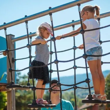 Enfants escaladant un parcours d'escalade en corde au Camping du Lac de Moselotte.