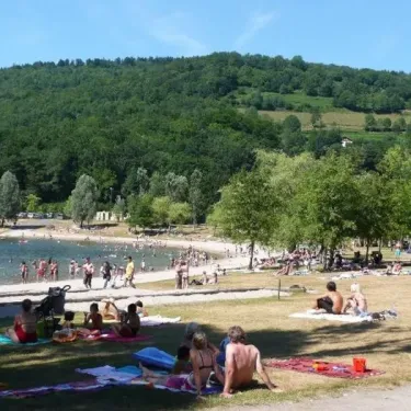 Camping du Lac de Moselotte : plage animée avec des visiteurs se baignant et se détendant sous un ciel bleu.