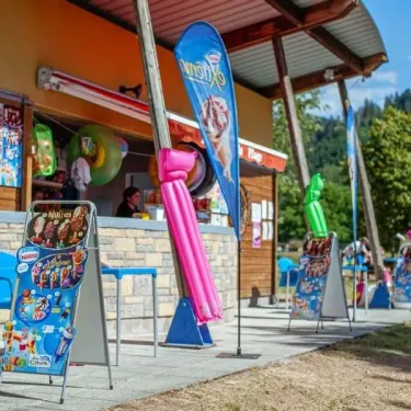 Booth glaceries avec affiches de produits et chaises bleues, Camping du Lac de Moselotte